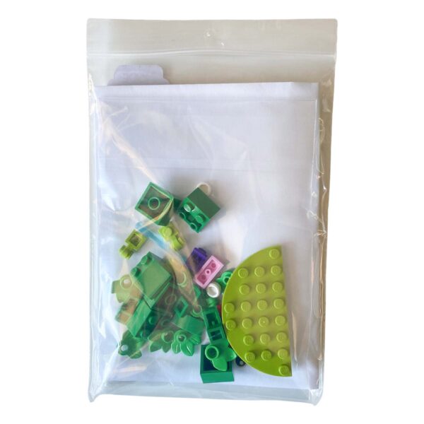 Individual LEGO pieces for the mini frog brick build laid out beside the greeting card