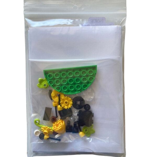 Individual LEGO pieces for the mini bee brick build laid out beside the greeting card