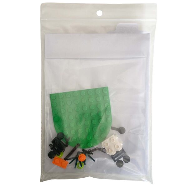 Individual LEGO pieces for the mini mower brick build laid out beside the greeting card